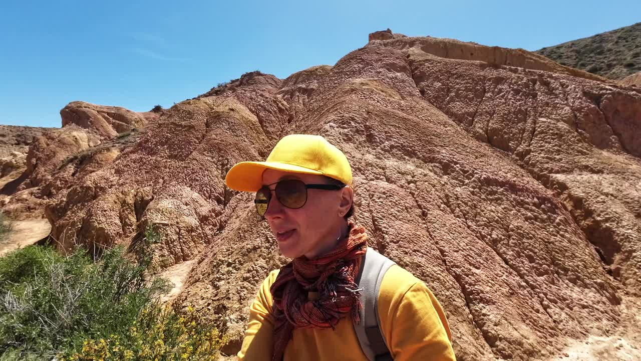 在一个令人惊叹的峡谷的心脏，开朗的成熟女性徒步旅行者与一群着迷的观众分享她的快乐视频下载