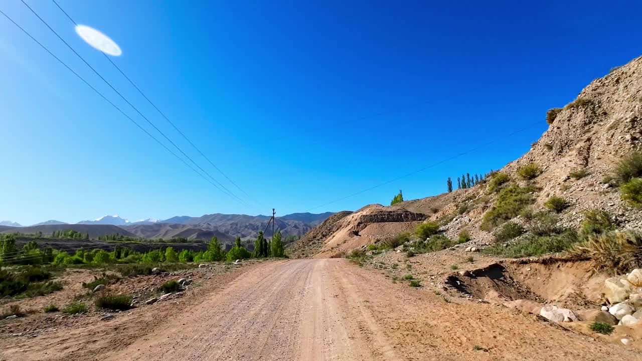 春天，蜿蜒的沙道穿过青翠的高原山谷视频下载