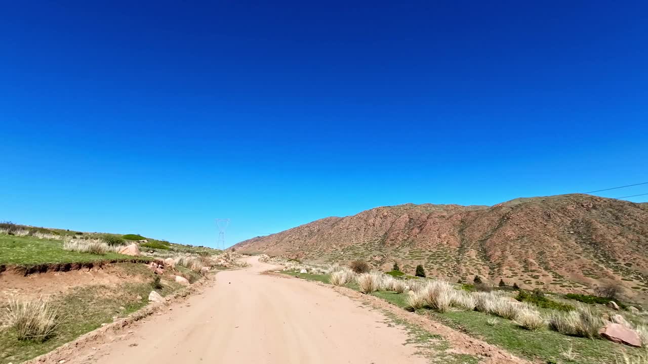 在半干旱的高原山谷中，沿着土路稳步攀登，周围是干旱的景观视频下载