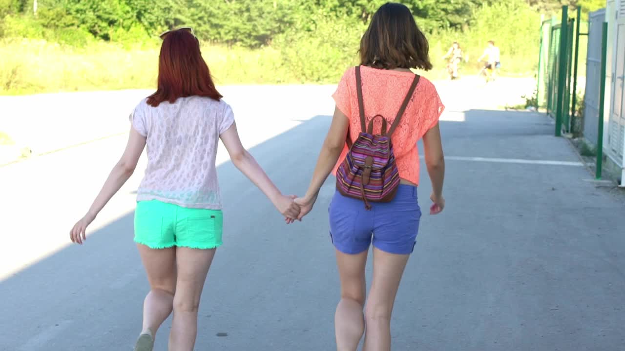 两个女性朋友在街上手牵着手一起跳视频下载