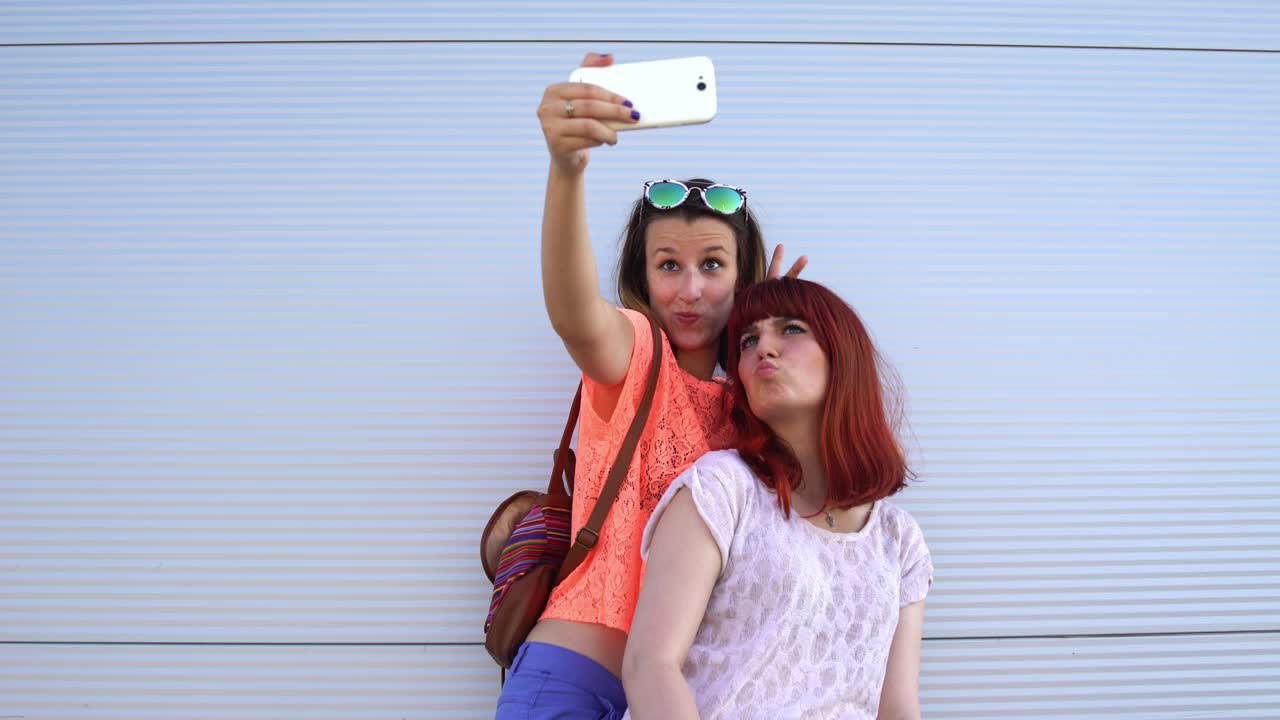 两个女性朋友在户外用智能手机自拍视频下载