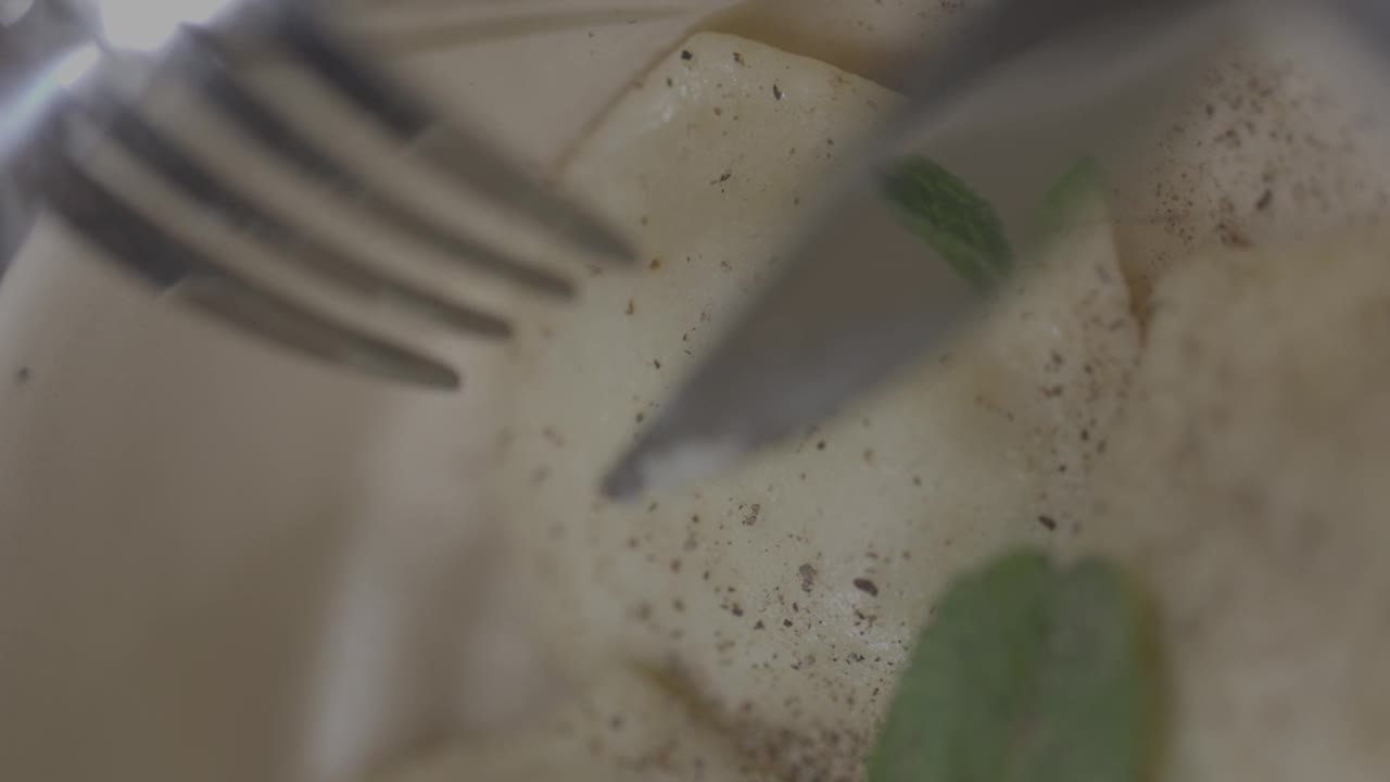 特写镜头的饺子在瓷盘与餐刀和叉子在模糊的前景视频下载
