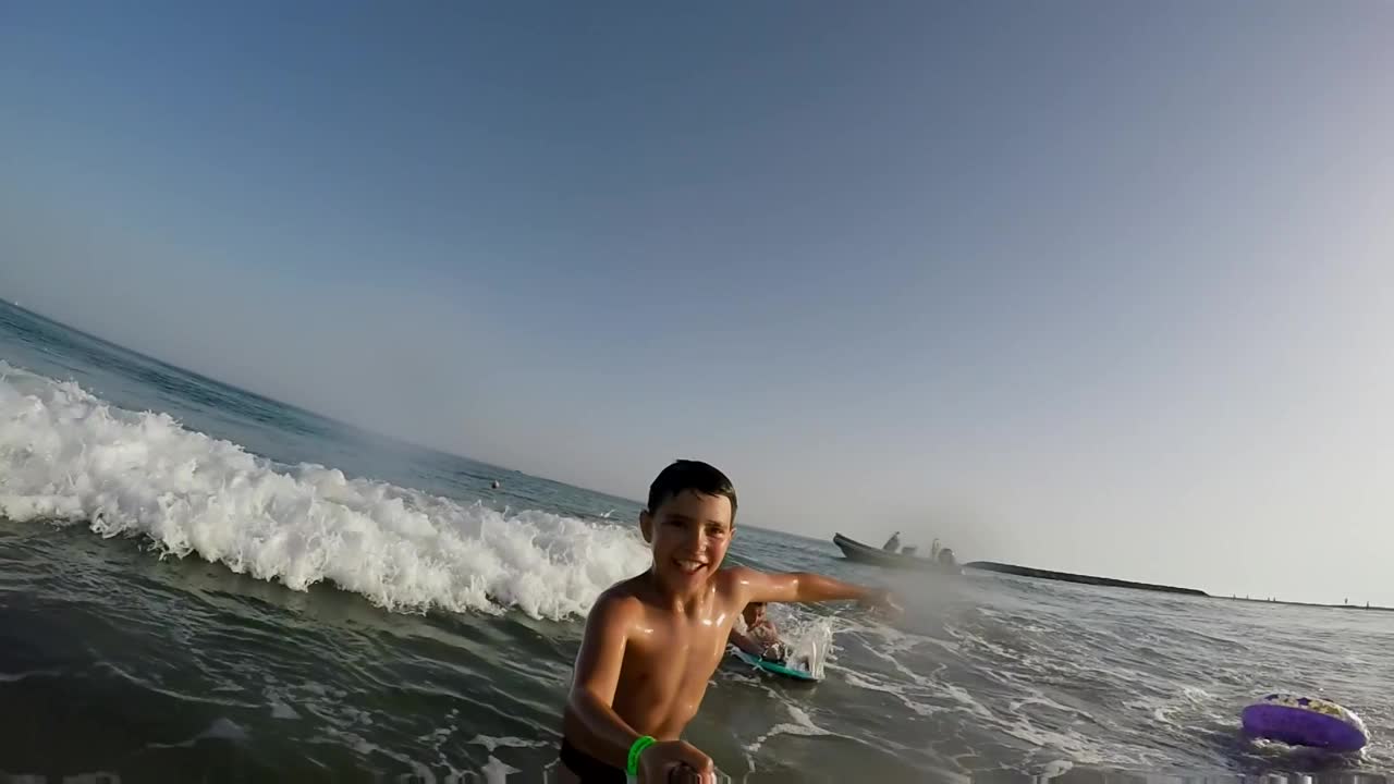 微笑的男孩正在等待一个巨大的海浪打破海岸视频下载