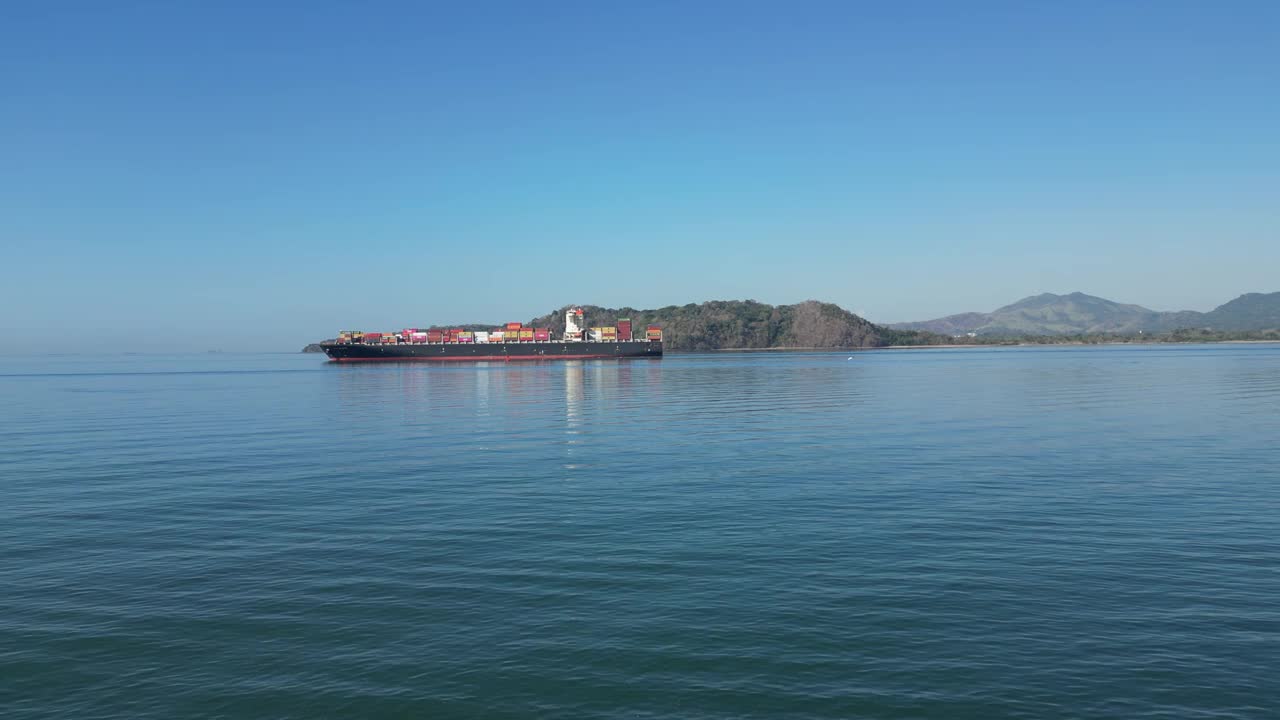 巴拿马运河的照片，背景是一艘满载集装箱和山丘的船。视频下载