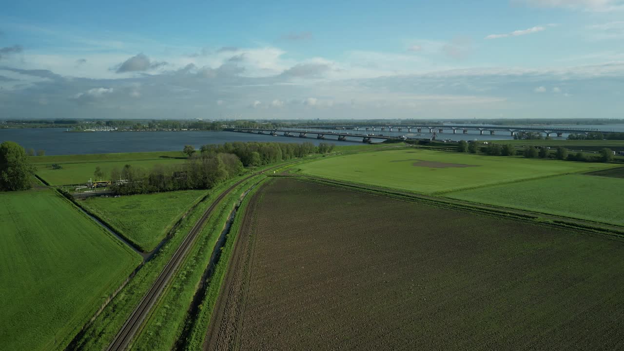 无人机在荷兰沿着一条火车轨道拍摄的可耕地和一条河流。视频下载