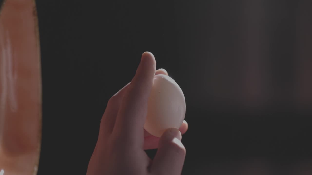 在一个瓷碗里打鸡蛋的慢动作特写镜头，背景是模糊的黑色视频下载