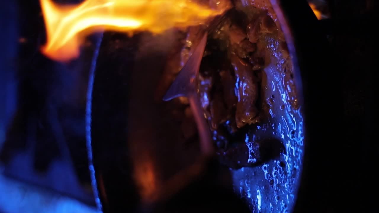 用平底锅煎猪肝，在昏暗的蓝光下用抹刀搅拌的特写镜头视频下载