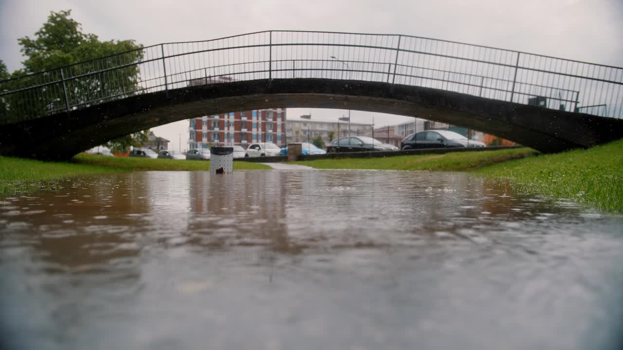 城市中的下雨天:被水淹没的公园和被水淹没的道路上的桥梁视频下载