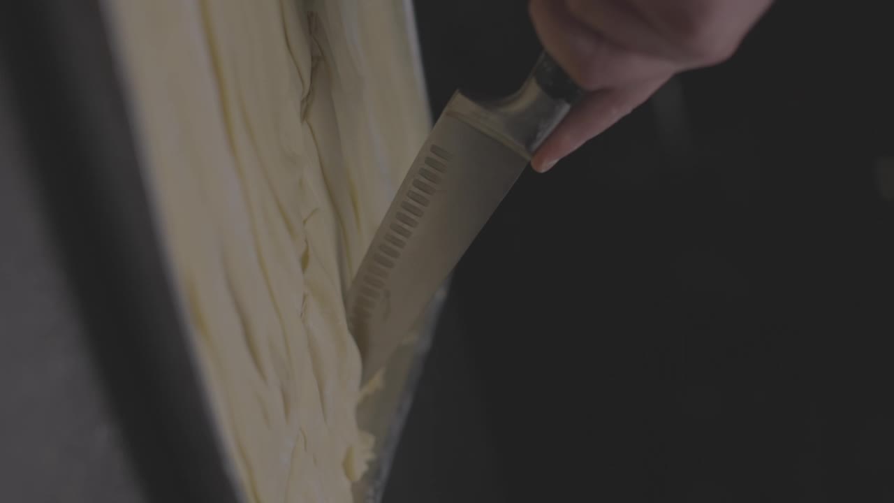 用刀在金属器皿中切面团的特写慢动作，背景是黑色的视频下载