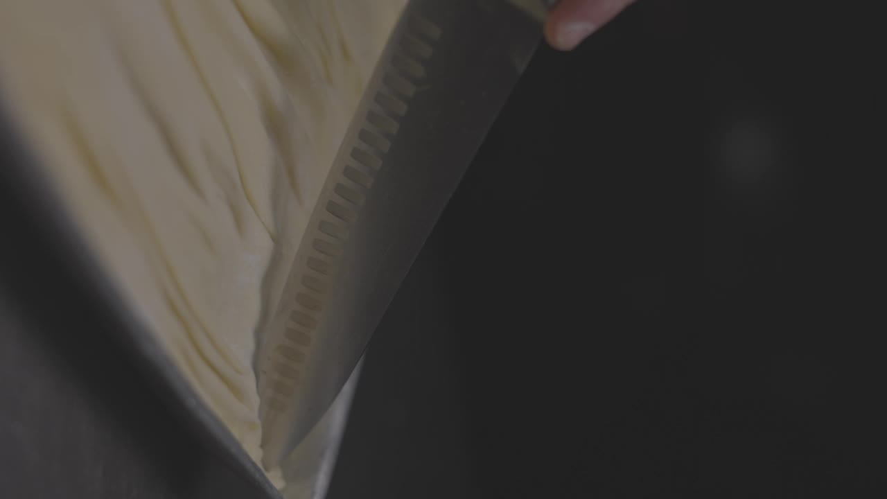 用刀在金属器皿中切面团的特写慢动作，背景是黑色的视频下载