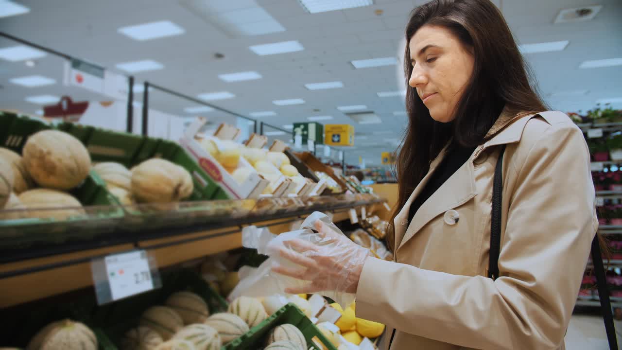 一名妇女戴上一次性生态手套在商店购买新鲜食品。视频下载