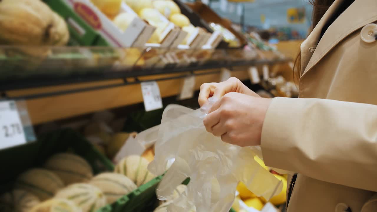 一名妇女戴上一次性生态手套在商店购买新鲜食品。视频下载
