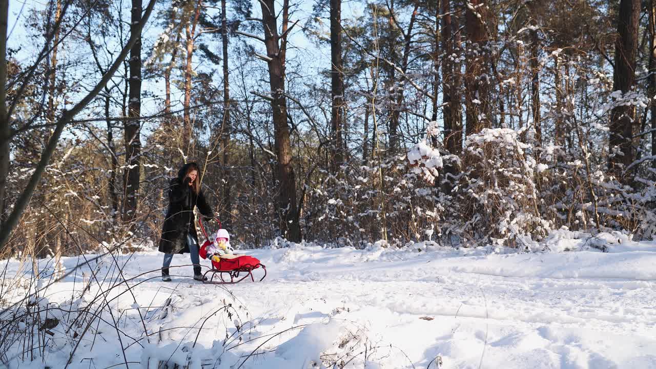 冬天，妈妈带着孩子在森林里散步。视频下载