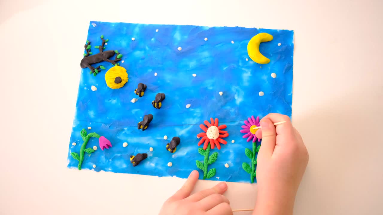 孩子在硬纸板上涂上彩色橡皮泥，制作童话卡片、花朵、月光、童话之夜视频下载
