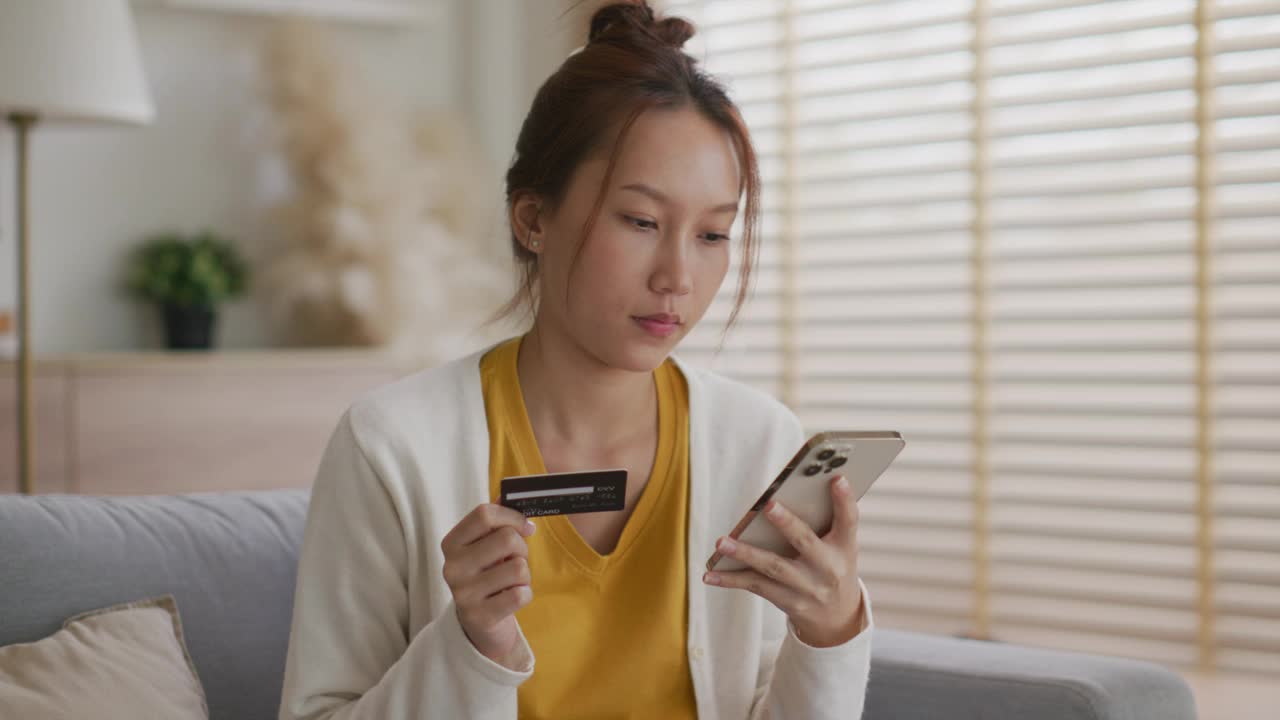 年轻女子用信用卡在智能手机上购物视频下载