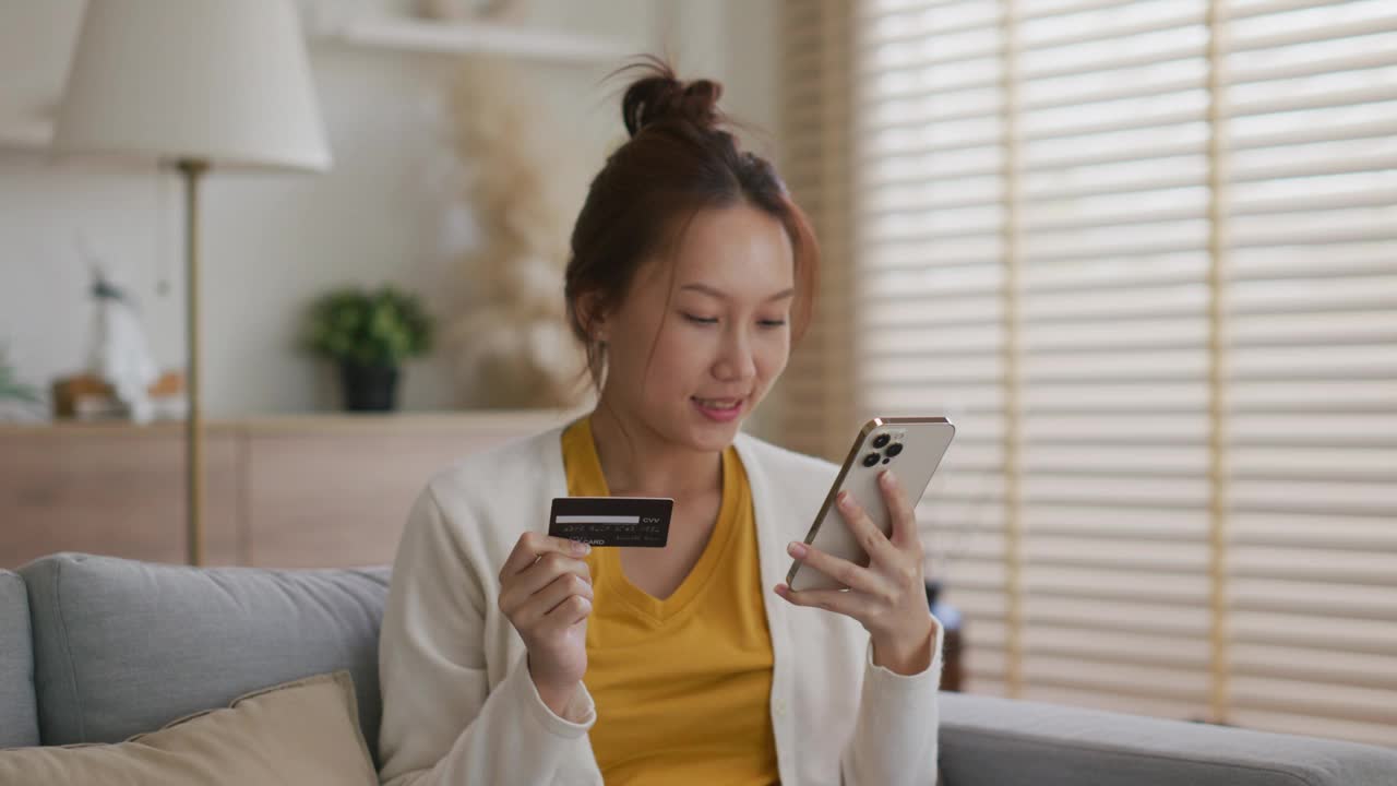 年轻女子用信用卡在智能手机上购物视频下载