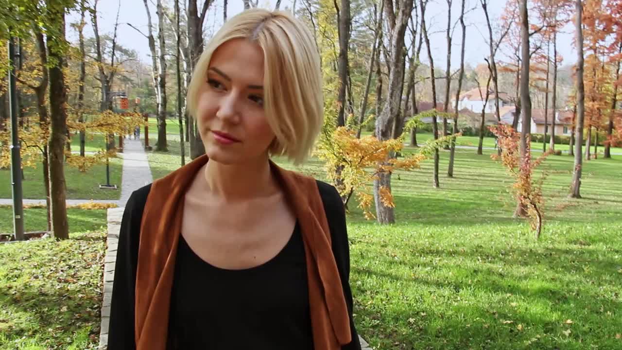在秋天的公园里散步的金发女郎视频下载