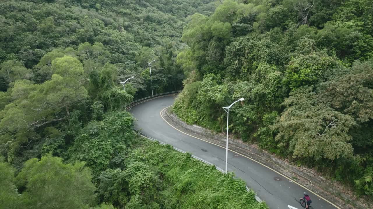 无人机拍摄的年轻亚洲女子骑自行车在农村道路上视频下载
