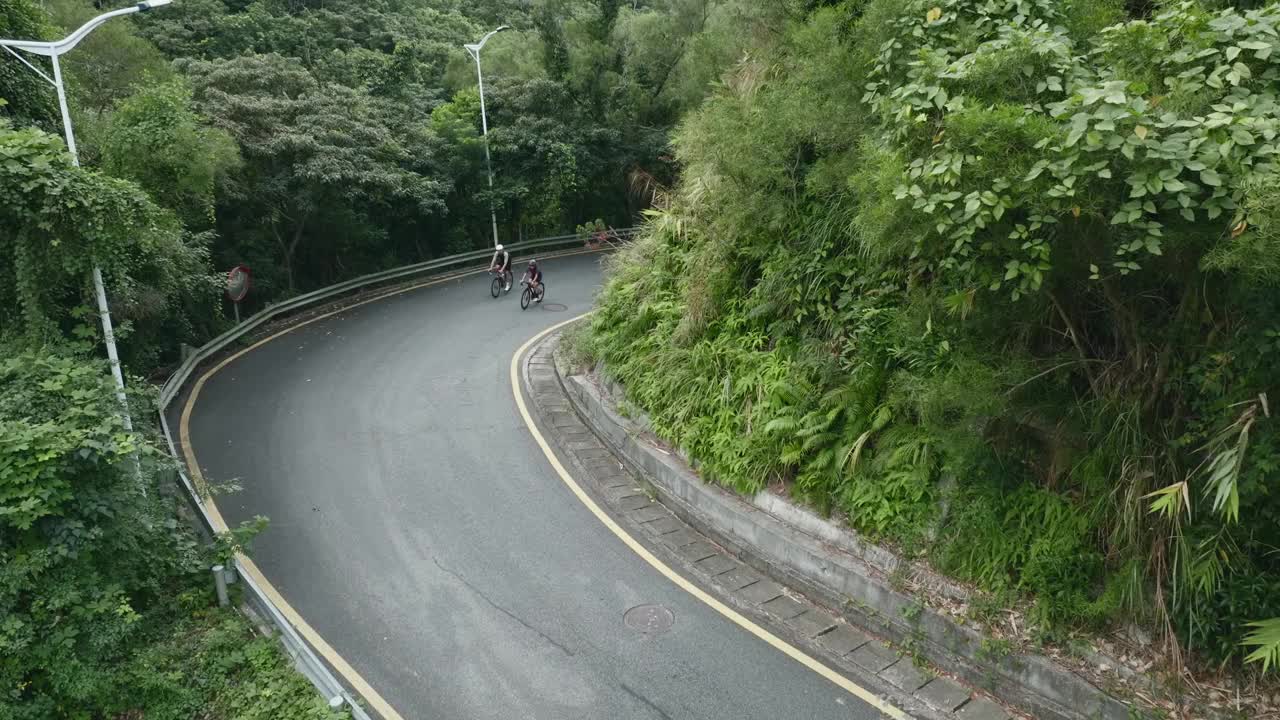 无人机拍摄的年轻亚洲夫妇骑自行车在农村道路上视频下载
