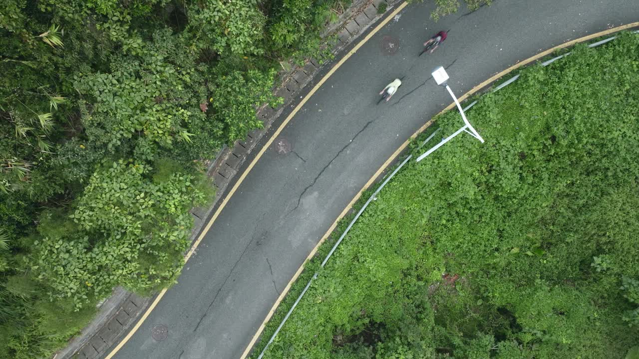 无人机拍摄的年轻亚洲骑自行车的人在农村道路上骑自行车视频下载