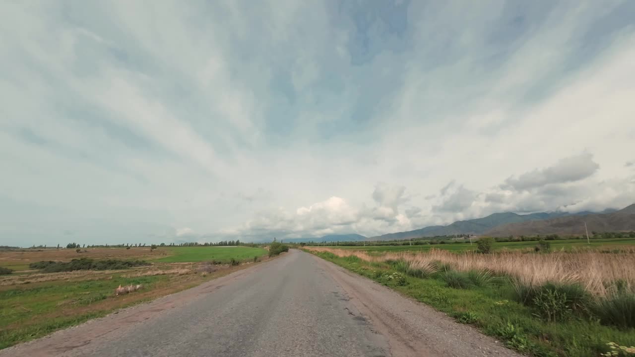 在多云的天空下，田野间狭窄的道路视频下载