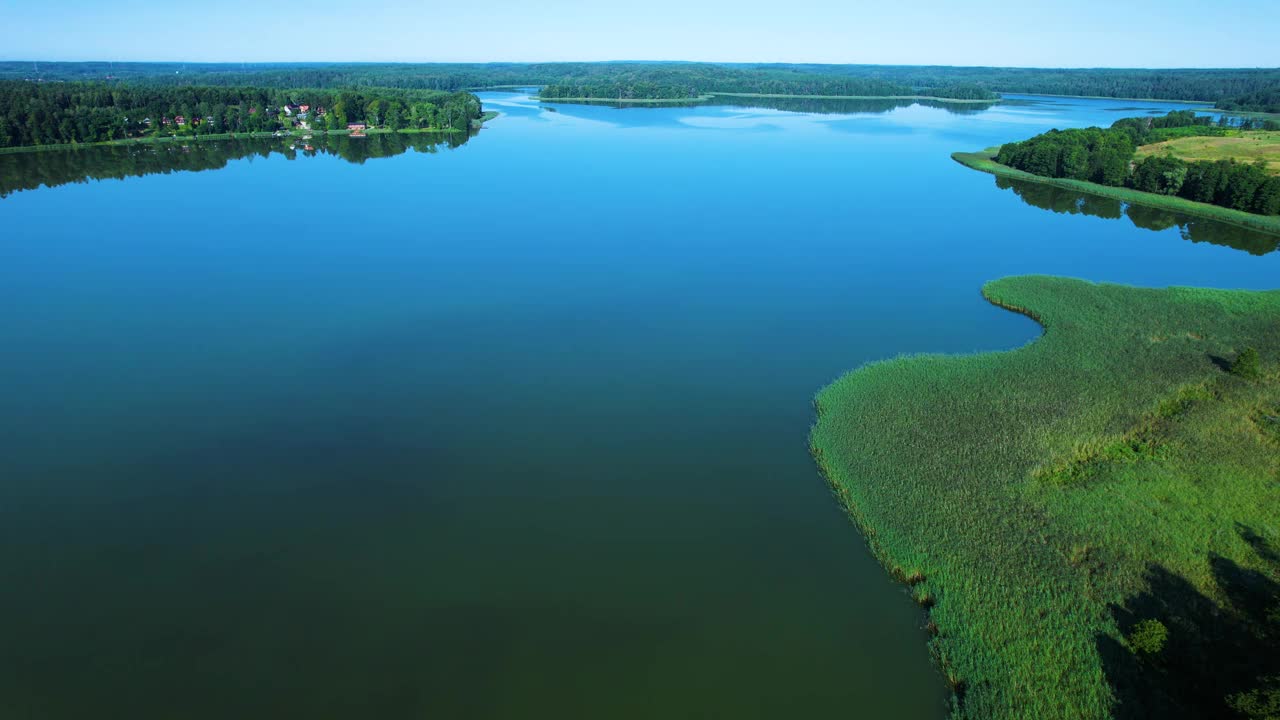 壮丽的鸟瞰平静的湖泊与岛屿在波兰。天堂湖岸边的乡村房屋。水面上的宁静。壮观美丽的湖鸟瞰图。史诗般的惊人的自然景观。视频下载