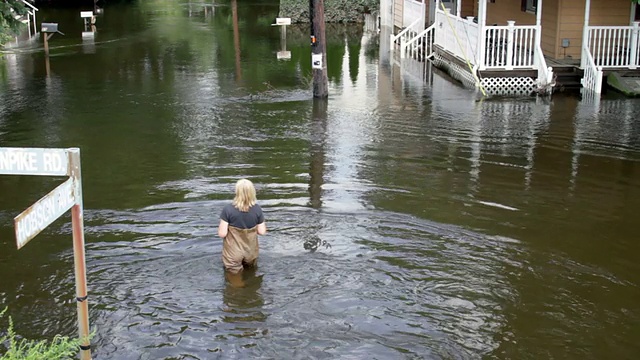 一名妇女走过被洪水淹没的社区视频素材
