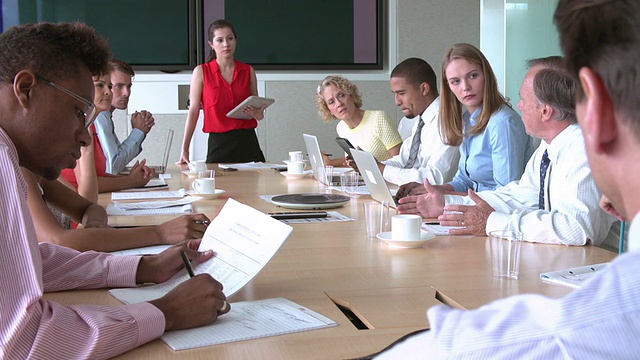 女商人向围坐在会议室桌旁的一群同事讲话。用索尼FS700拍摄，帧率25帧/秒视频下载