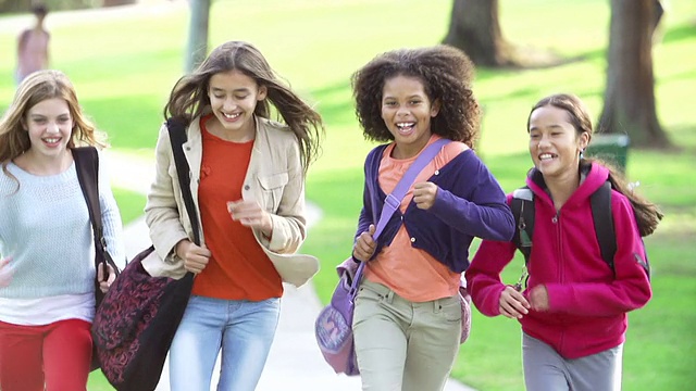 在公园里，年轻女孩用慢动作跑向摄像机视频素材