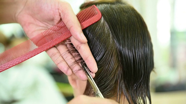 美容师的手用梳子剪着女人的头发视频下载