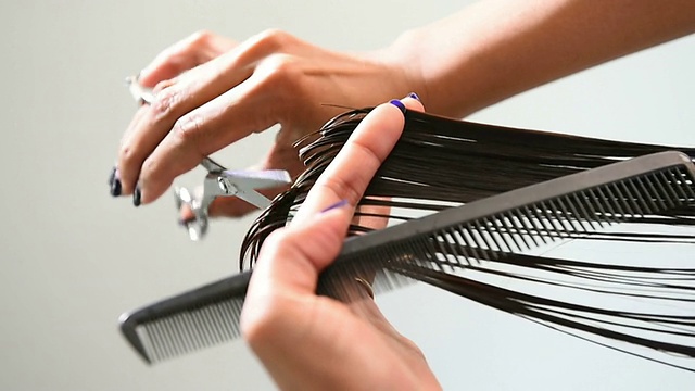 美容师的手用梳子剪着女人的头发视频下载
