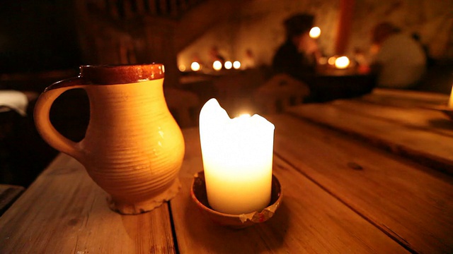 在爱沙尼亚首都塔林的一家老餐馆里，木头桌子上燃着蜡烛和瓷杯视频素材