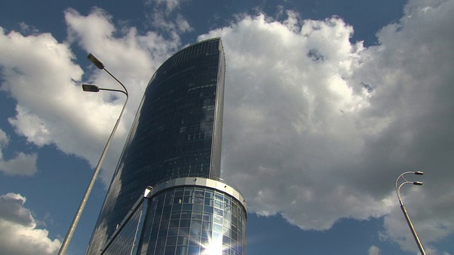 在飞翔的云的背景上有镜像的摩天大楼。延时。视频素材