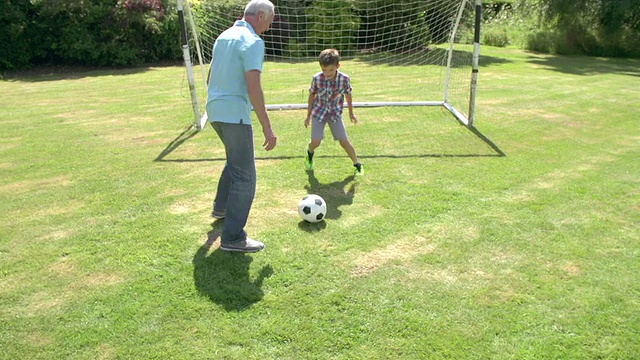 爷爷和孙子在家花园里踢足球视频素材