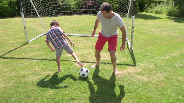 爸爸和儿子在家里的花园里踢足球视频下载