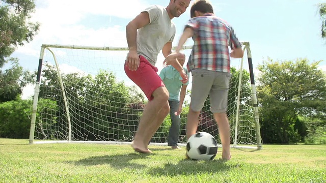 爷爷、孙子和爸爸在花园里踢足球视频素材