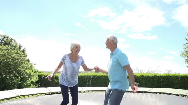 一对老年夫妇在蹦床上慢动作跳跃视频下载