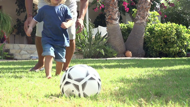 爷爷和孙子在花园里踢足球视频素材