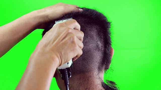 一个男孩正在用剪子理发，绿色的屏风视频下载