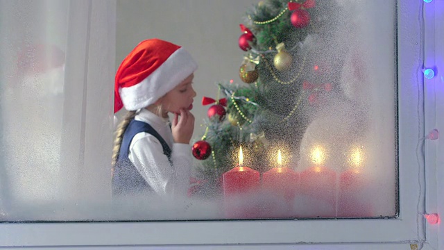 有趣的孩子们围绕着窗外装饰好的树景庆祝圣诞节视频下载