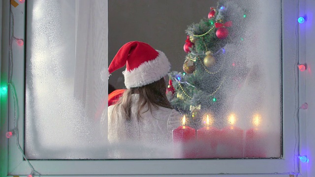 透过窗户看着孩子们围着装饰好的圣诞树视频下载
