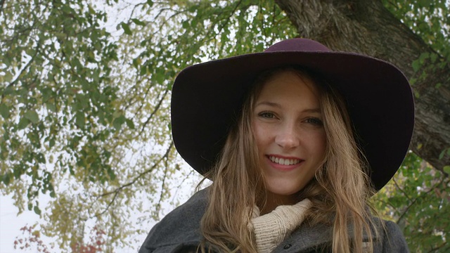 一位戴着帽子的可爱年轻女子低头看着镜头微笑着视频素材