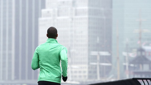 一名男子在雨中在纽约摩天大楼前慢跑，远离镜头视频素材