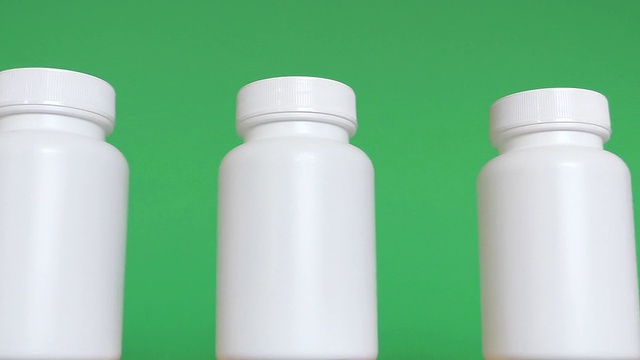 一排白色瓶子在绿色背景下孤立视频下载