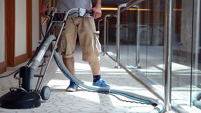 清洁男工人正在清洁酒店走廊的地毯视频素材