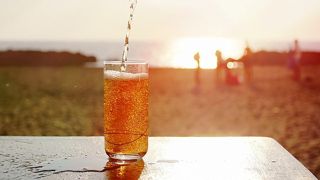 在海滩边倒着一杯鸡尾酒:夏天，日落，慢镜头视频素材