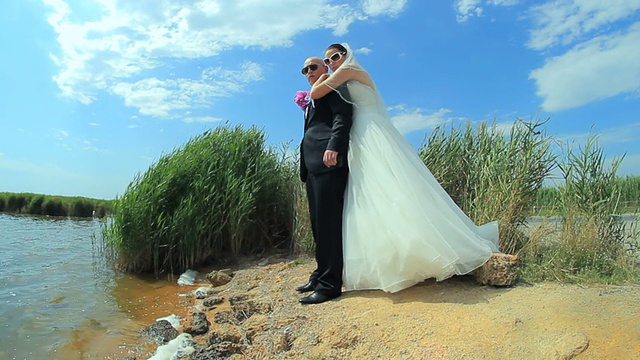 年轻美丽的新婚夫妇在池塘边互相拥抱和亲吻视频下载