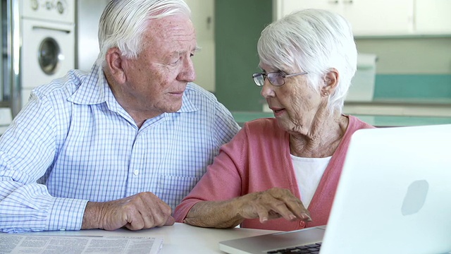 一对老年夫妇在厨房里使用笔记本电脑视频素材