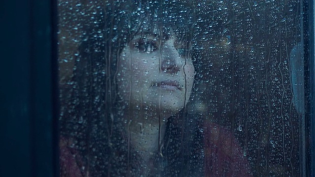 在雨天，窗后沉思的女人。在slowmotion拍摄视频下载