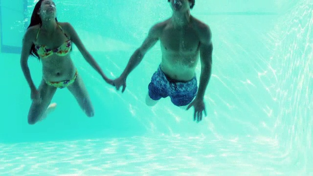 一对快乐的情侣一起在游泳池里跳视频素材